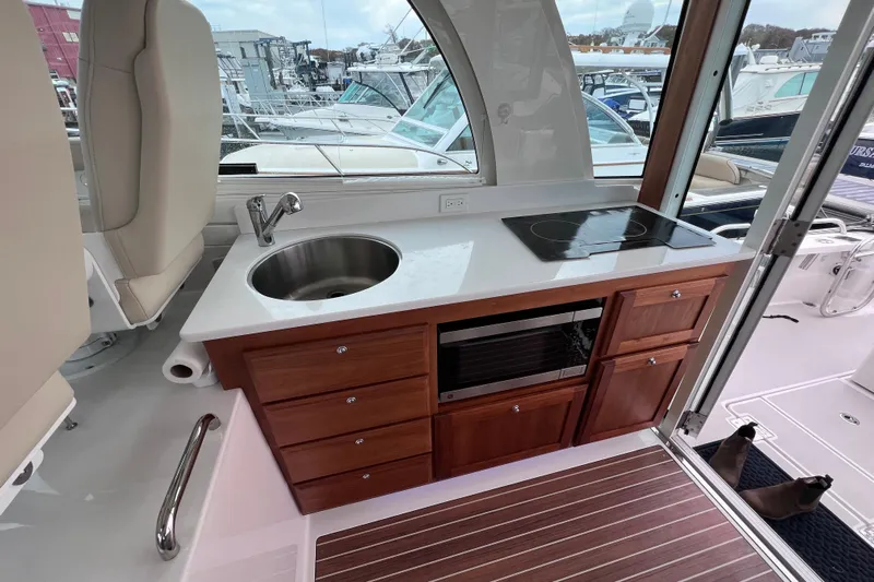 Wally World Yacht Photos Pics 2024 Back Cove 39O yacht interior with kitchenette, featuring sink, stove, and wooden cabinetry.
