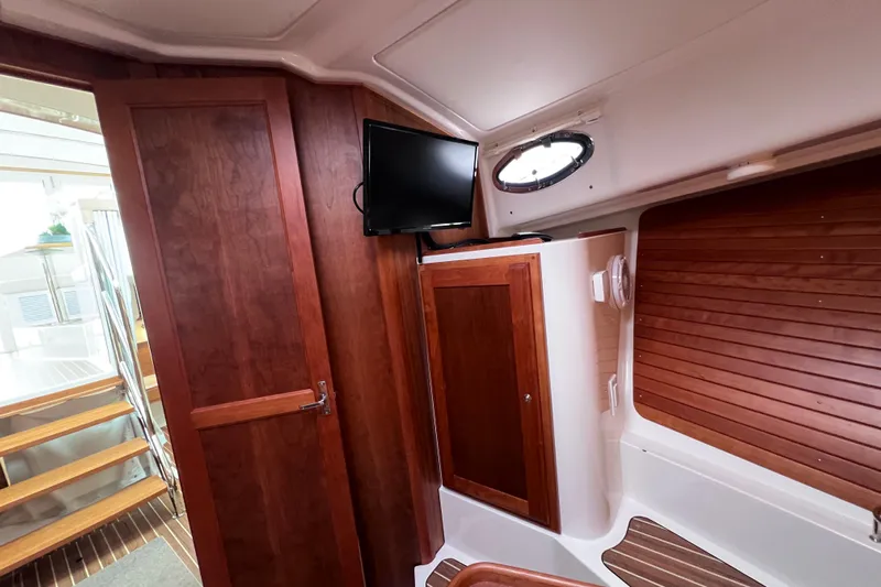 Wally World Yacht Photos Pics 2024 Back Cove 39O interior with wood paneling, TV, and stairs.