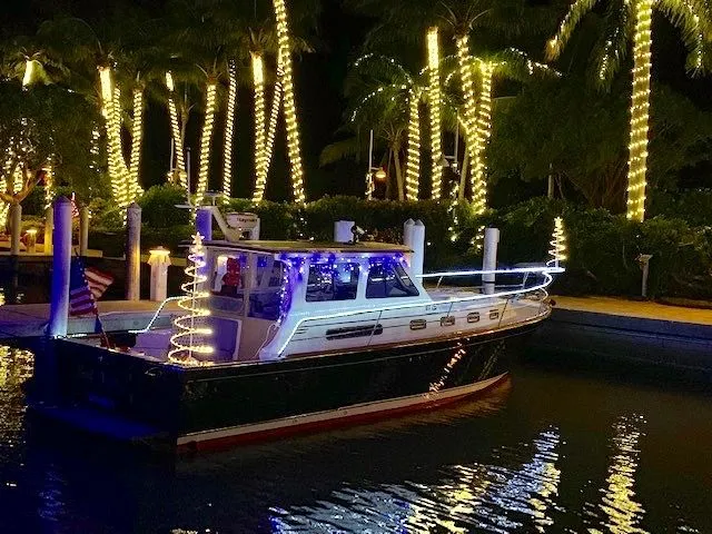 Gulf Kart Lll Yacht Photos Pics Illuminated 2003 Sabre 36 boat at night, surrounded by palm trees.