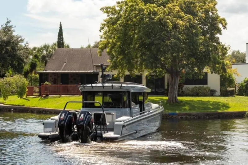 Yacht Photos Pics 2024 BRABUS Shadow 1000XC boat cruising on a serene river near a house.