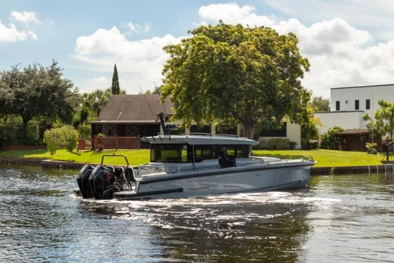  Yacht Photos Pics 2024 BRABUS Shadow 1000XC boat cruising on a scenic river near houses.