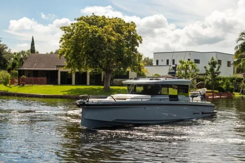  Yacht Photos Pics 2024 BRABUS Shadow 1000XC yacht cruising on a serene river near modern homes.