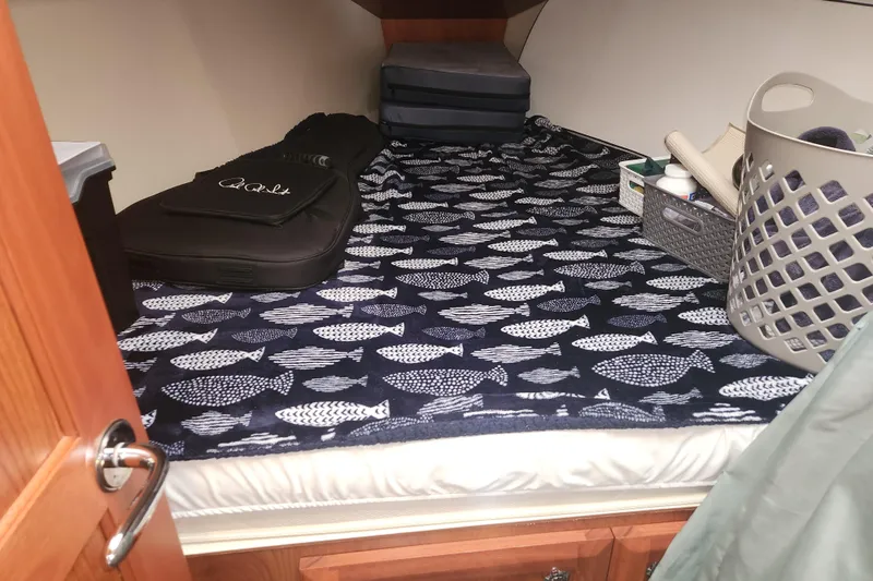 Antares Yacht Photos Pics Cozy cabin interior of 2011 Hunter 39 sailboat with fish-patterned bedding and storage items.