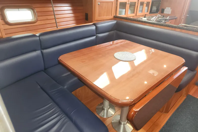 Antares Yacht Photos Pics Luxurious 2011 Hunter 39 yacht interior with blue seating and wooden dining table.
