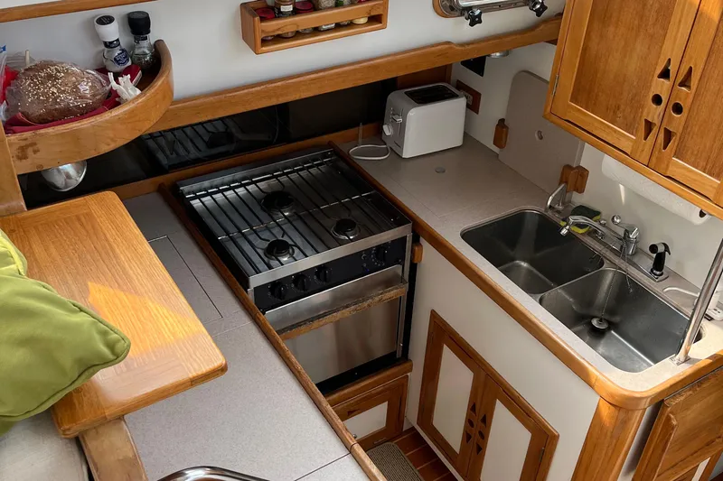 Spirit Yacht Photos Pics 2001 Cabo Rico Northeast 400 yacht kitchen with stove, sink, and wooden cabinetry.