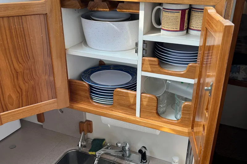 Spirit Yacht Photos Pics Wooden kitchen cabinet with neatly organized dishes and mugs on a Cabo Rico Northeast 400 yacht.