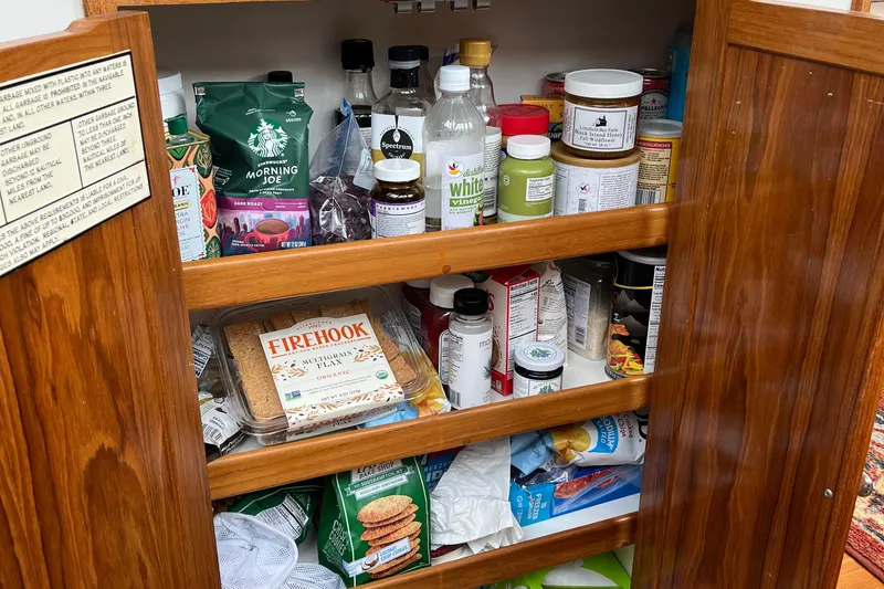 Spirit Yacht Photos Pics Wooden pantry on Cabo Rico Northeast 400 yacht, stocked with various food items and beverages.