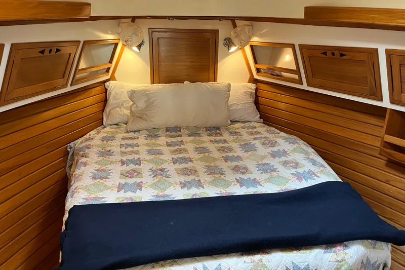 Spirit Yacht Photos Pics Cozy cabin interior of 2001 Cabo Rico Northeast 400 with wooden paneling and quilted bedding.