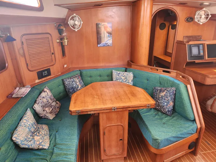Lea Scotia Yacht Photos Pics Interior of 1989 Taswell 43 yacht with wooden table and green cushioned seating.