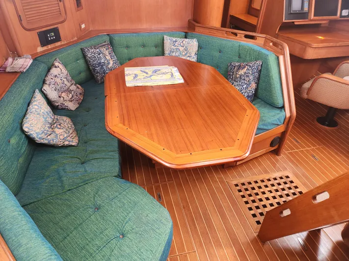 Lea Scotia Yacht Photos Pics Interior of 1989 Taswell 43 yacht with wooden table, green seating, and patterned cushions.