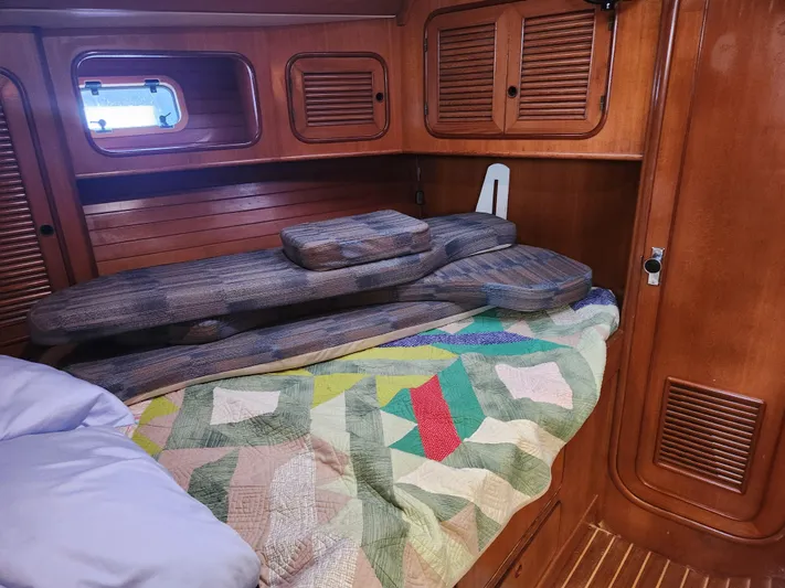 Lea Scotia Yacht Photos Pics Cozy cabin interior of 1989 Taswell 43 sailboat with colorful quilt and wooden paneling.