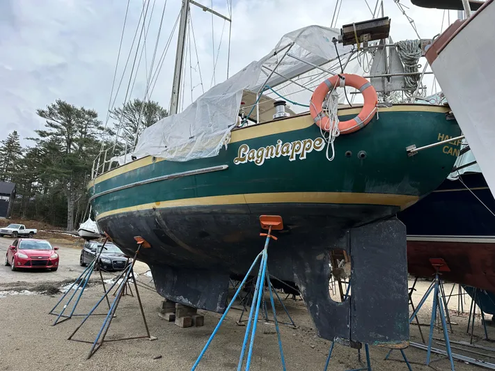 Lagniappe Yacht Photos Pics Pacific Seacraft Crealock 44 sailboat from 1990 on stands, covered with tarp, in a boatyard.