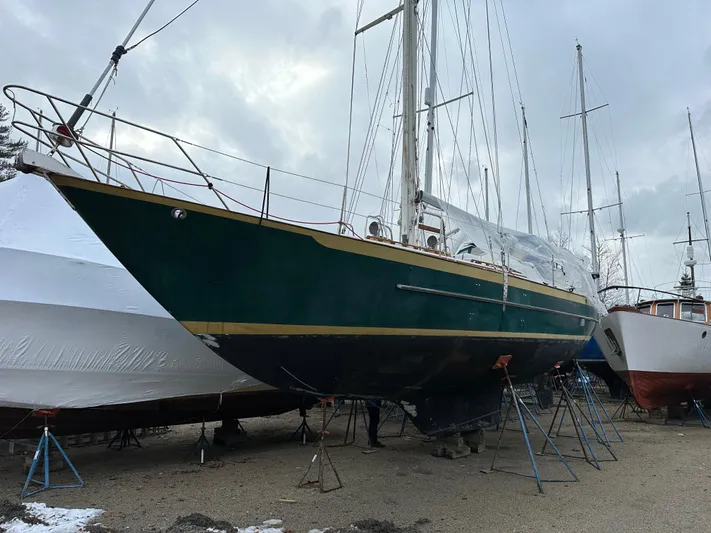 Lagniappe Yacht Photos Pics 1990 Pacific Seacraft Crealock 44 sailboat on stands, green hull, overcast sky.