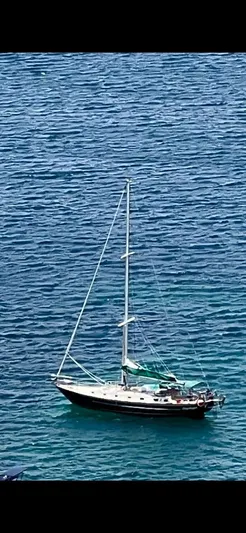 Lagniappe Yacht Photos Pics Sailboat Pacific Seacraft Crealock 44, 1990 model, anchored in clear blue water.