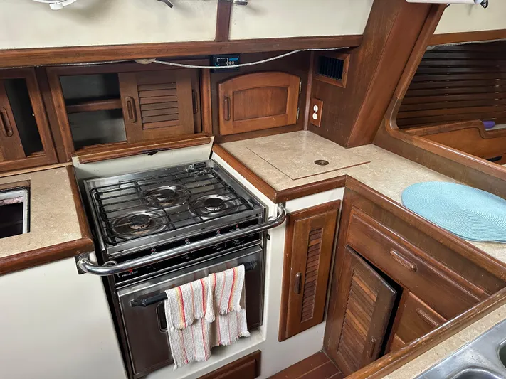 Lagniappe Yacht Photos Pics Galley of 1990 Pacific Seacraft Crealock 44 with stove, wooden cabinets, and countertop.