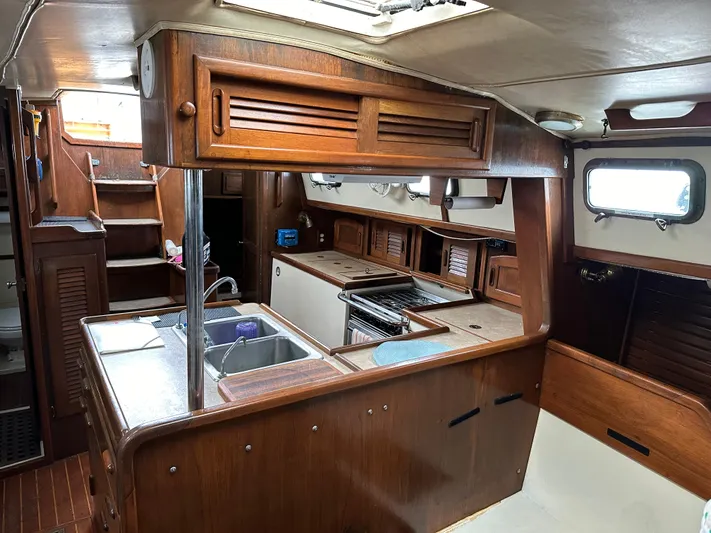 Lagniappe Yacht Photos Pics Interior of 1990 Pacific Seacraft Crealock 44 sailboat with wooden cabinetry and kitchen area.
