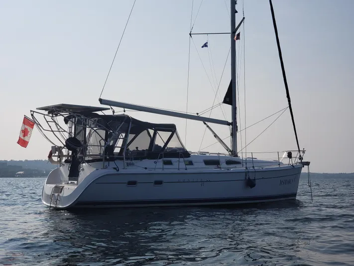 Inspiration VI Yacht Photos Pics 2006 Hunter 41 sailboat on calm water with a flag, side view.