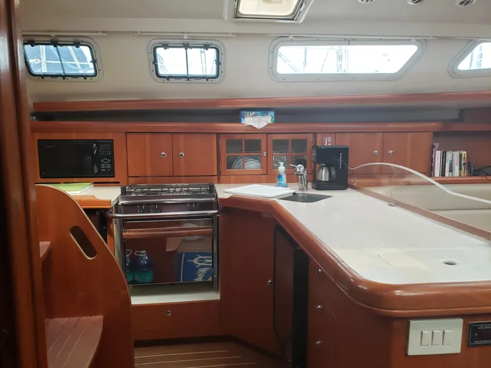 Inspiration VI Yacht Photos Pics 2006 Hunter 41 yacht interior kitchen with stove, microwave, and wooden cabinetry.