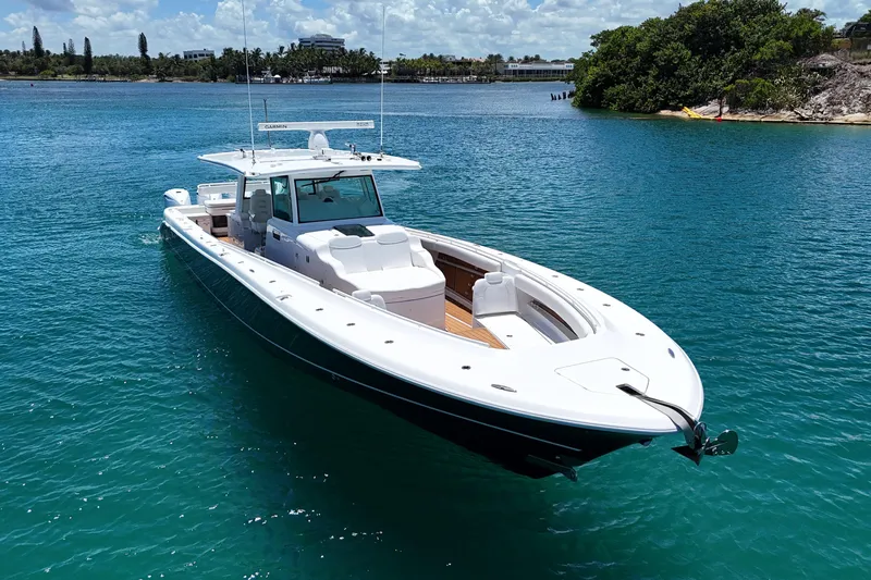  Yacht Photos Pics 2020 HCB 53 Sueños boat on clear blue water, near a lush shoreline.