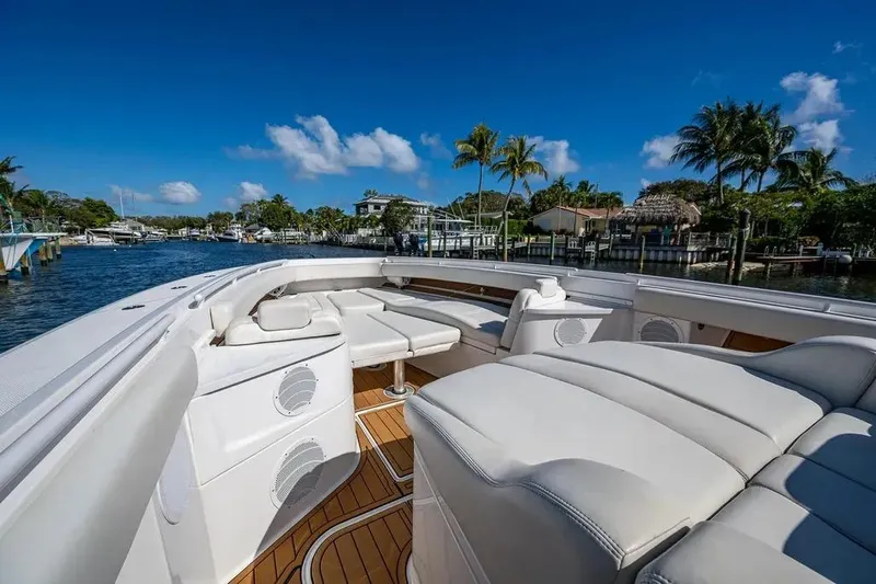  Yacht Photos Pics Luxury 2020 HCB 53 Sueños boat with spacious seating, docked near palm trees and waterfront homes.