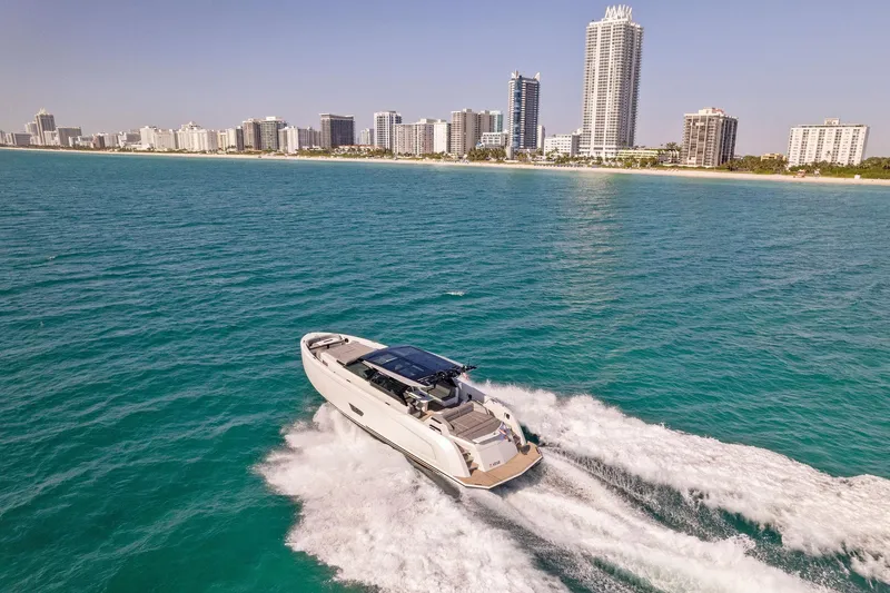 The Next Trade Yacht Photos Pics Vanquish Yachts VQ58 2022 cruising near a city skyline on clear blue waters.