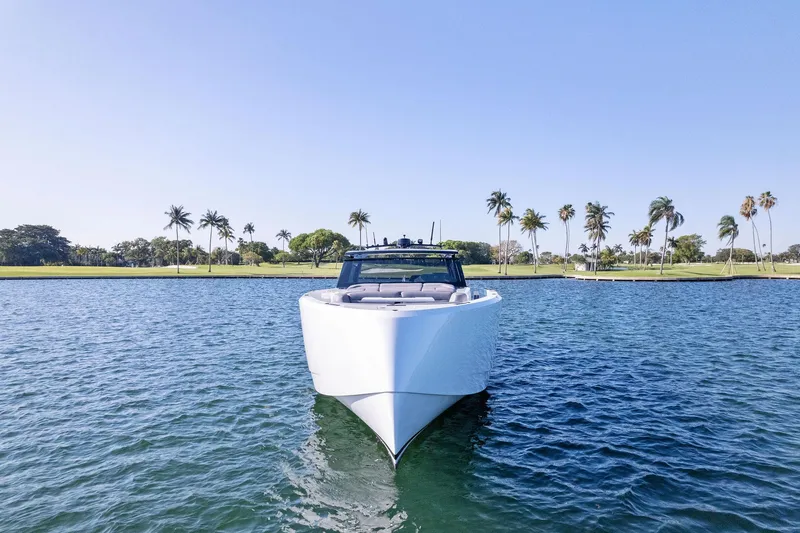 The Next Trade Yacht Photos Pics Vanquish Yachts VQ58 2022 on water, palm trees in background, clear blue sky.