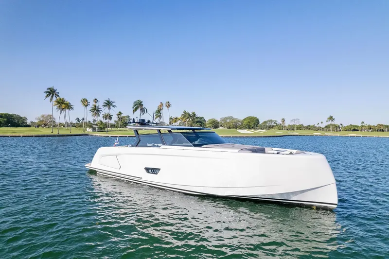 The Next Trade Yacht Photos Pics 2022 Vanquish Yachts VQ58 luxury yacht on serene water with palm trees in the background.