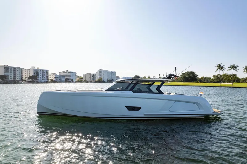 The Next Trade Yacht Photos Pics 2022 Vanquish Yachts VQ58 luxury yacht on calm water with cityscape background.