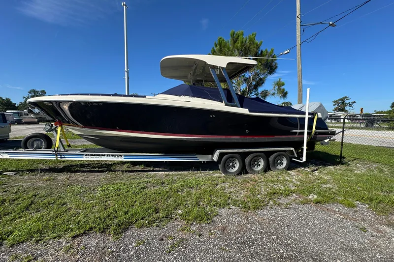  Yacht Photos Pics 2018 Chris-Craft Calypso 30 boat on trailer, parked outdoors under clear blue sky.
