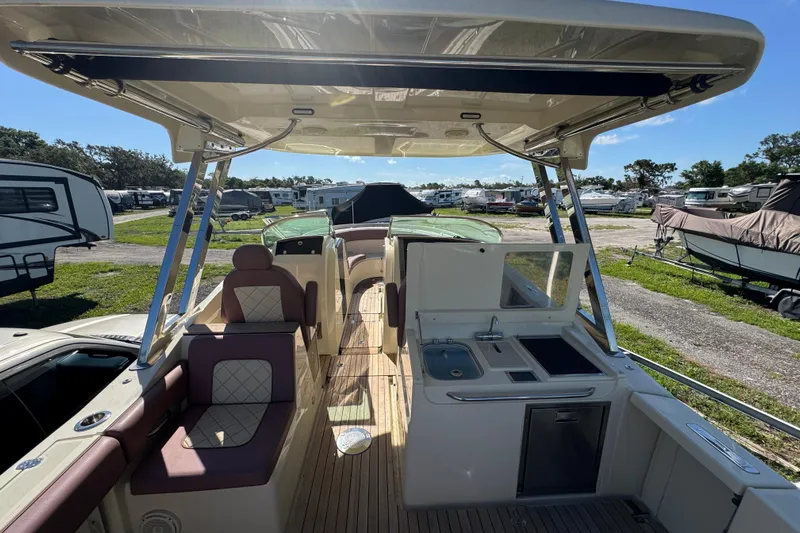  Yacht Photos Pics 2018 Chris-Craft Calypso 30 boat interior with seating and kitchenette, parked outdoors.