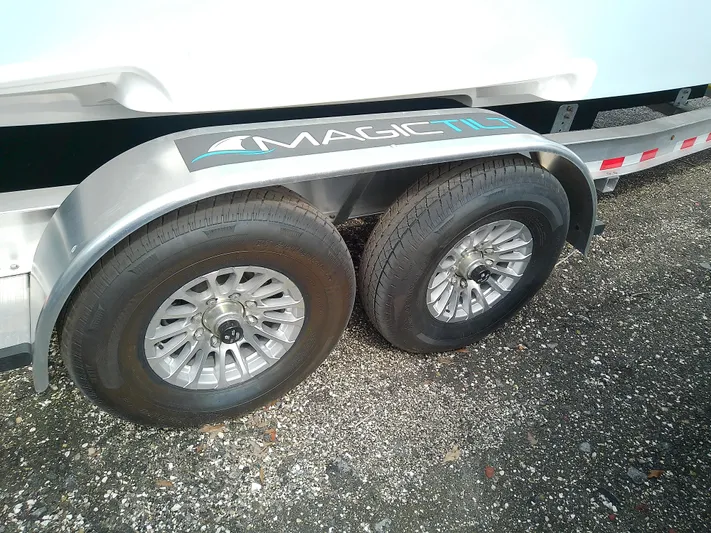  Yacht Photos Pics Trailer wheels of a 2025 Glasstream 328 SCX boat on gravel surface.