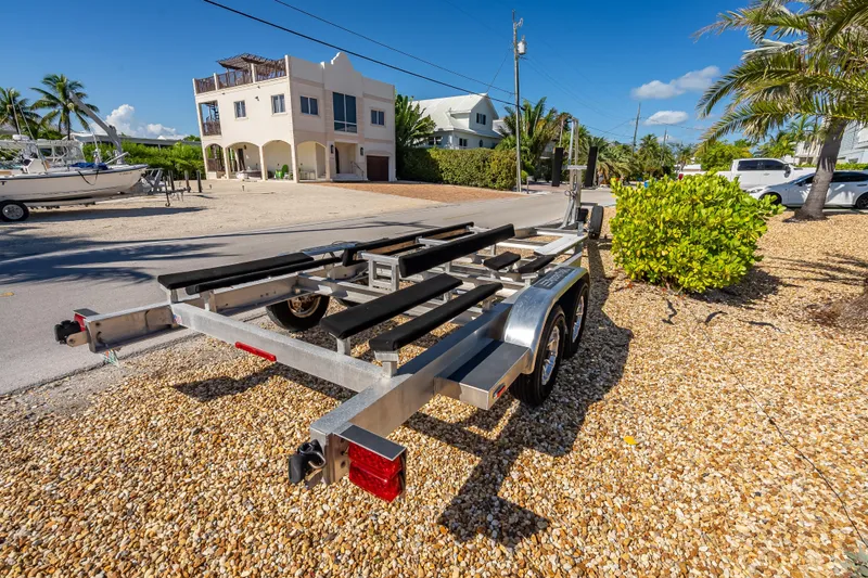  Yacht Photos Pics Trailer for 2022 Costa Custom Boats 264, parked on gravel near palm trees and houses.