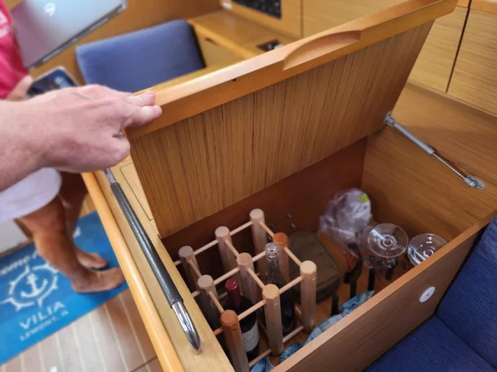 Vilia Yacht Photos Pics Interior of 2010 Jeanneau 45DS yacht with open wooden storage compartment holding wine bottles and glasses.