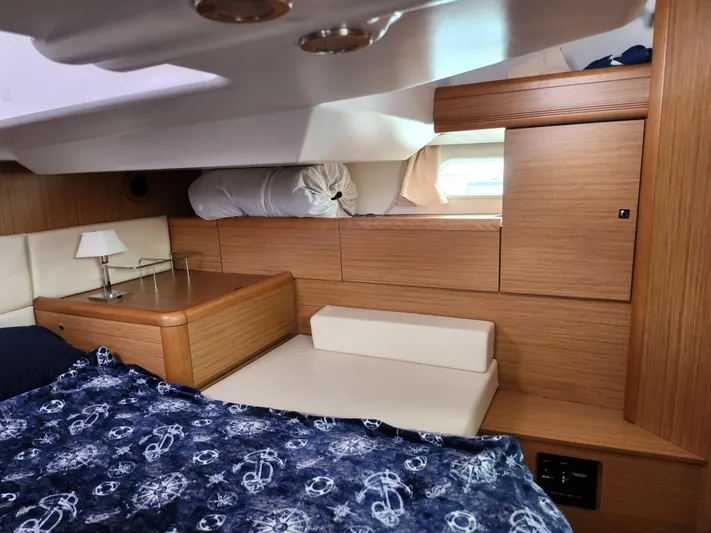 Vilia Yacht Photos Pics Interior of 2010 Jeanneau 45DS yacht cabin with wooden finish and nautical-themed blanket.