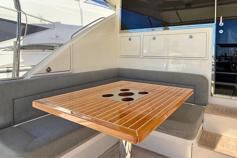 Buzz Yacht Photos Pics Luxurious seating area on 2020 Riviera 57 Enclosed Flybridge yacht with wooden table.