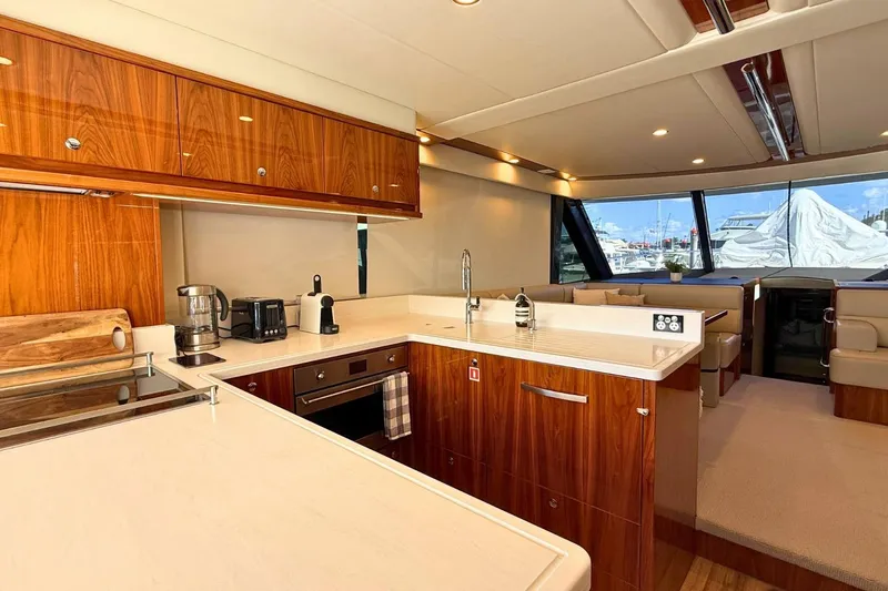 Buzz Yacht Photos Pics Luxurious interior of 2020 Riviera 57 Enclosed Flybridge yacht with modern kitchen and seating area.