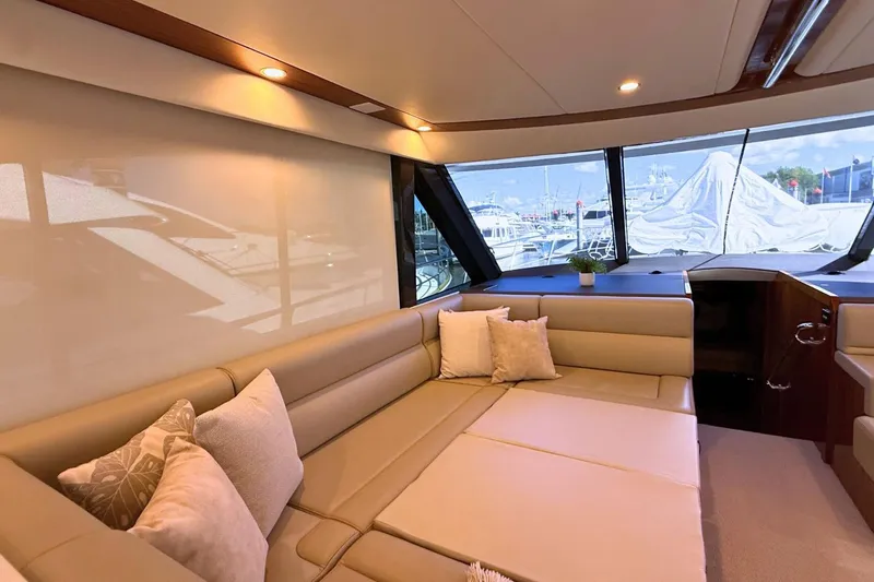 Buzz Yacht Photos Pics Luxurious interior of 2020 Riviera 57 Enclosed Flybridge yacht with plush seating and large windows.