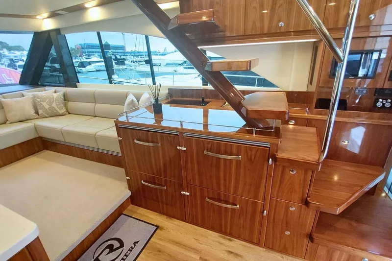 Buzz Yacht Photos Pics Luxurious interior of 2020 Riviera 57 Enclosed Flybridge yacht with elegant wood finish.