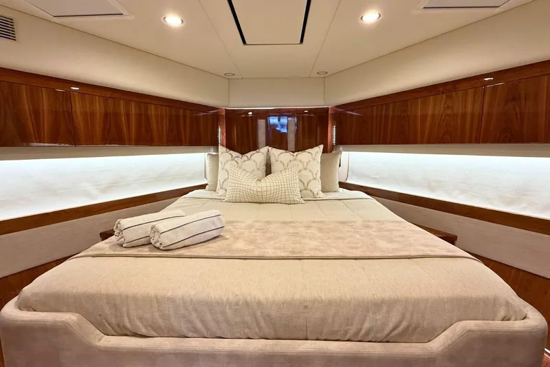 Buzz Yacht Photos Pics Luxurious bedroom interior of 2020 Riviera 57 Enclosed Flybridge yacht with elegant wood finishes.