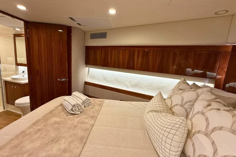 Buzz Yacht Photos Pics Luxurious bedroom interior of 2020 Riviera 57 Enclosed Flybridge yacht with elegant wood finishes.