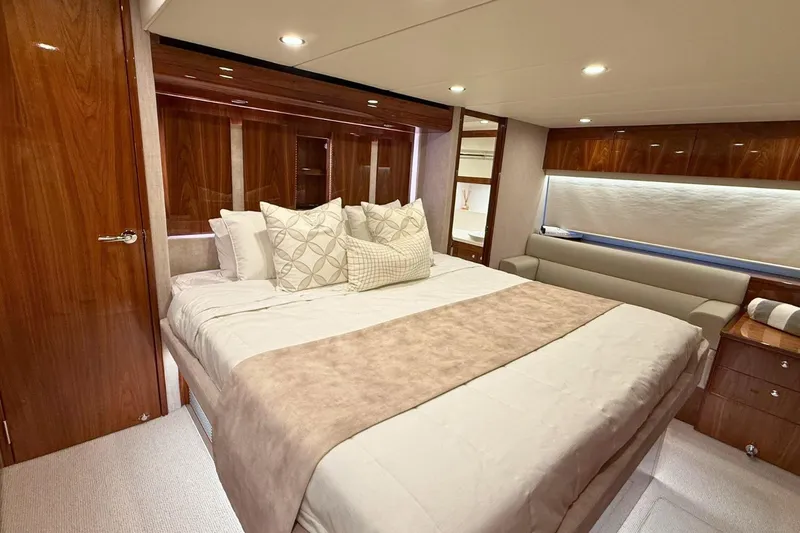 Buzz Yacht Photos Pics Luxurious bedroom interior of 2020 Riviera 57 Enclosed Flybridge yacht, featuring elegant wood finishes.