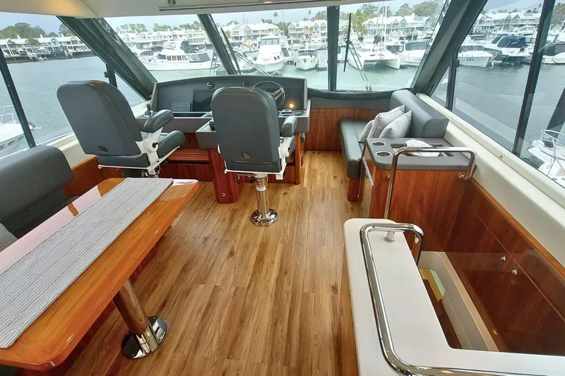 Buzz Yacht Photos Pics Luxurious interior of 2020 Riviera 57 Enclosed Flybridge yacht with panoramic windows and elegant seating.