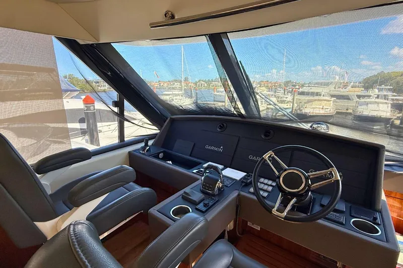 Buzz Yacht Photos Pics 2020 Riviera 57 Enclosed Flybridge helm with Garmin navigation, overlooking marina.