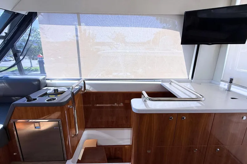 Buzz Yacht Photos Pics Interior of 2020 Riviera 57 Enclosed Flybridge with modern wood finish and TV.