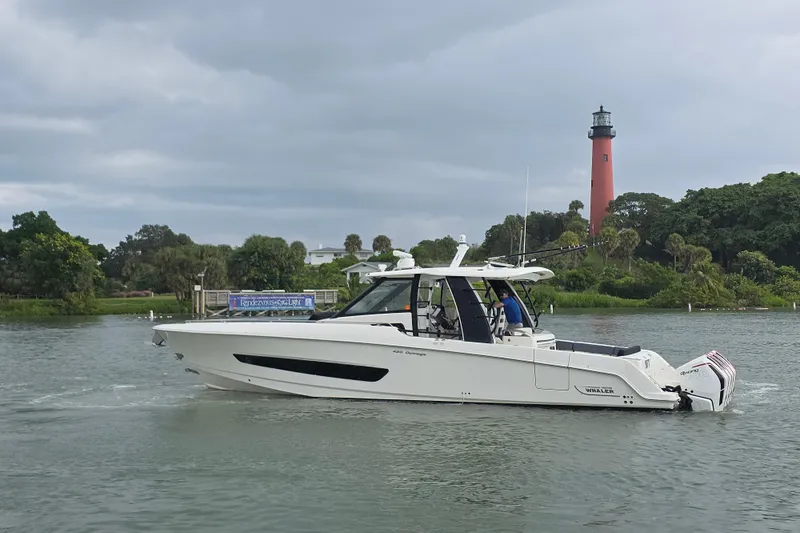 Bft Yacht Photos Pics 2021 Boston Whaler 420OR boat cruising near a lighthouse on a cloudy day.