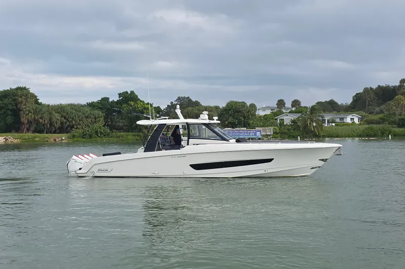Bft Yacht Photos Pics 2021 Boston Whaler 420OR boat cruising on a calm waterway with lush greenery.