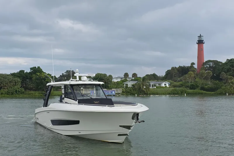 Bft Yacht Photos Pics 2021 Boston Whaler 420OR boat on water near a lighthouse, under cloudy skies.