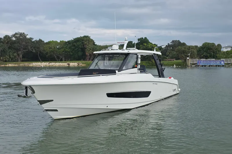 Bft Yacht Photos Pics 2021 Boston Whaler 420OR boat on calm water, surrounded by lush greenery.