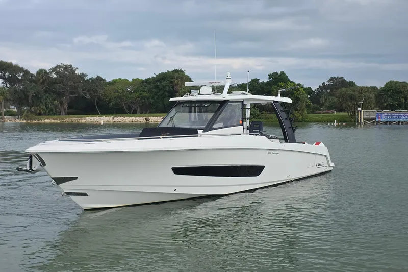Bft Yacht Photos Pics 2021 Boston Whaler 420OR boat on calm water, surrounded by lush greenery.