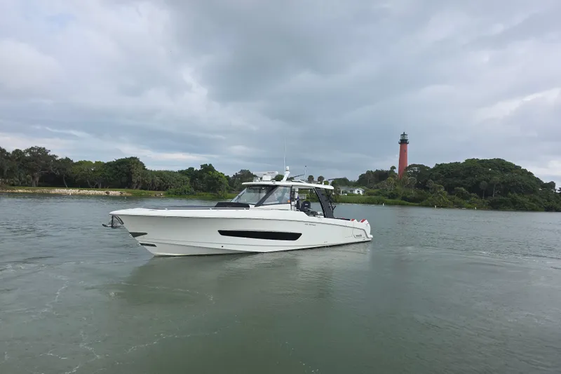 Bft Yacht Photos Pics 2021 Boston Whaler 420OR boat cruising near a lighthouse on a cloudy day.